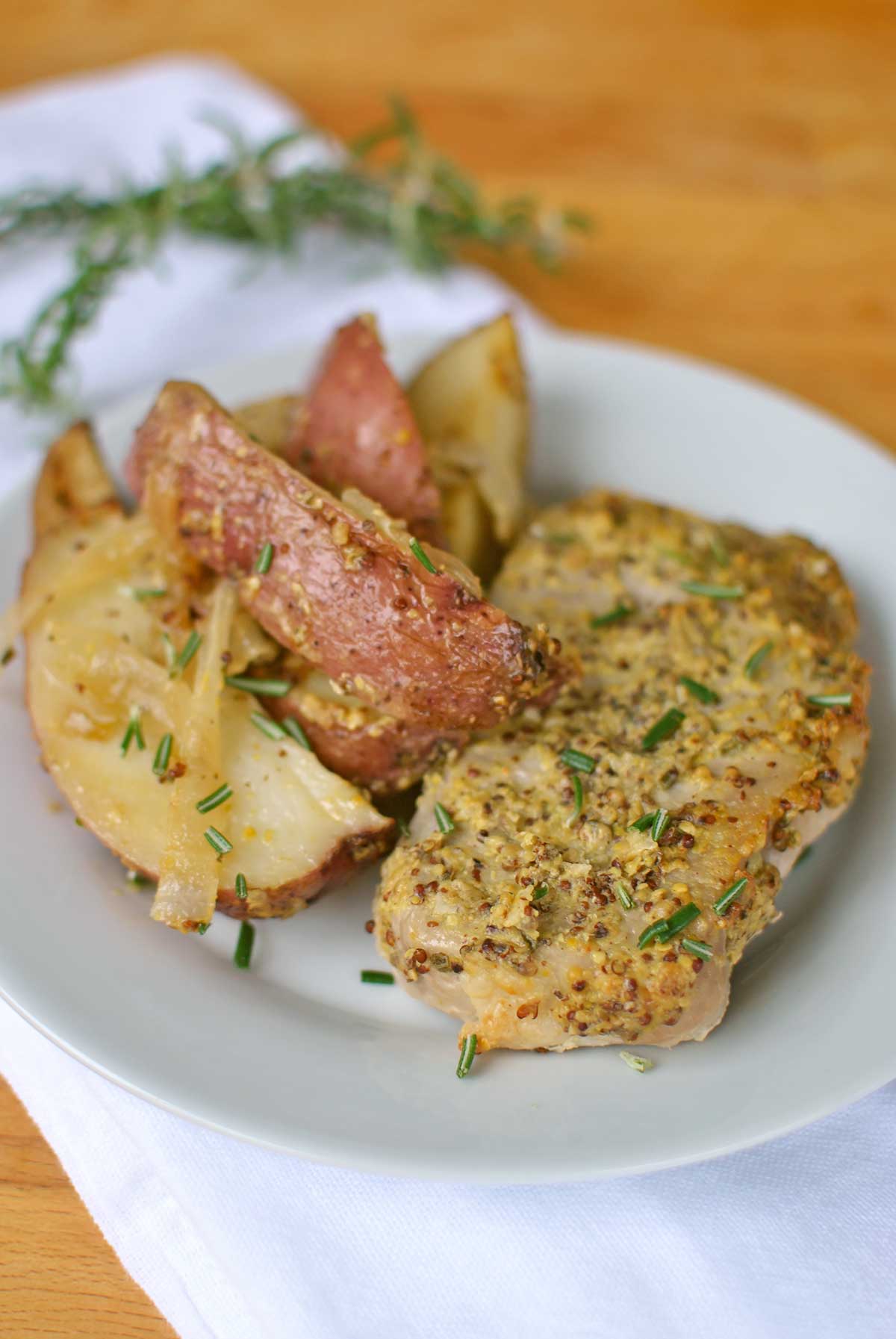 Roasted Rosemary Dijon Pork Chops and Potatoes is an easy one baking dish wonder! Fragrant rosemary and zesty dijon pair to make a flavorful basting sauce by Becky's Best Bites